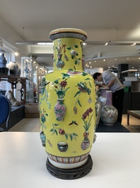 A pair of Chinese famille rose yellow-ground relief-decorated vases with wooden stands, 19th C.