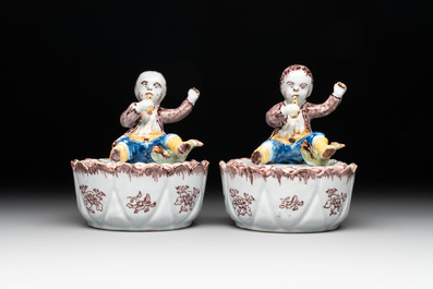 A pair of polychrome Dutch Delft fluting-children-topped butter tubs and covers, 18th C.