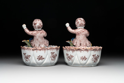A pair of polychrome Dutch Delft fluting-children-topped butter tubs and covers, 18th C.