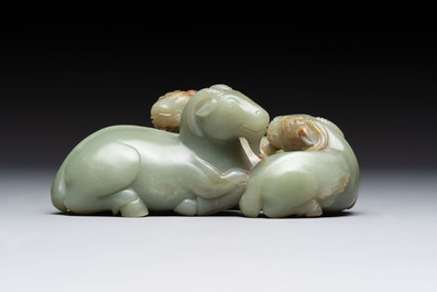 A Chinese celadon jade group of three goats on wooden stand, 19/20th C.
