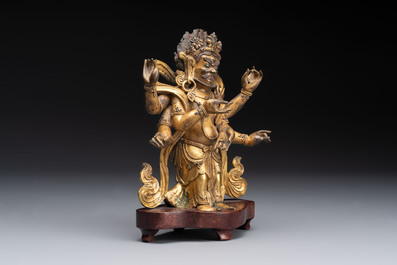A Sino-Tibetan gilt-bronze figure of White Mahakala on wooden stand, 18th C.