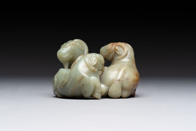 A Chinese celadon jade group of three goats on wooden stand, 19/20th C.