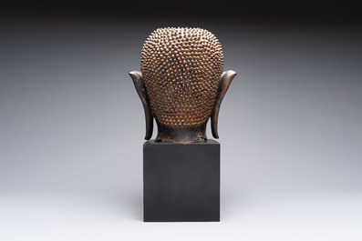A large Thai bronze Shakyamuni Buddha head on wooden stand, Chieng Sen period, 16th C.