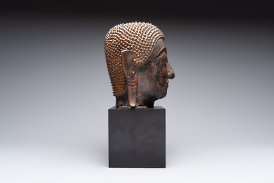 A large Thai bronze Shakyamuni Buddha head on wooden stand, Chieng Sen period, 16th C.