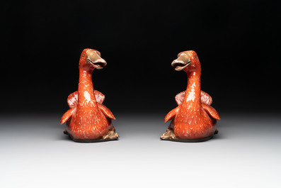 A pair of Chinese partly gilt coral-red-glazed models of ducks on wooden stands, 20th C.