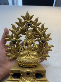 A Nepalese gilt-bronze Buddha on an inscribed throne with a mandorla, 19th C.