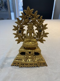 A Nepalese gilt-bronze Buddha on an inscribed throne with a mandorla, 19th C.