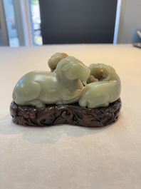 A Chinese celadon jade group of three goats on wooden stand, 19/20th C.