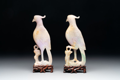 A pair of Chinese lavender and emerald-green jadeite parrots on wooden stands, 19th C.