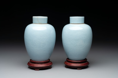 A pair of Chinese claire-de-lune jars and covers on wooden stands, Kangxi mark, 19th C.