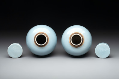 A pair of Chinese claire-de-lune jars and covers on wooden stands, Kangxi mark, 19th C.