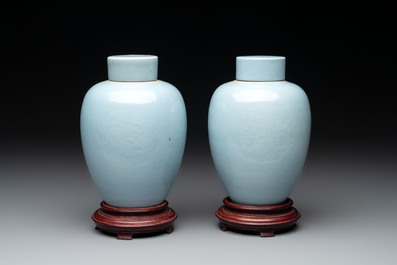 A pair of Chinese claire-de-lune jars and covers on wooden stands, Kangxi mark, 19th C.