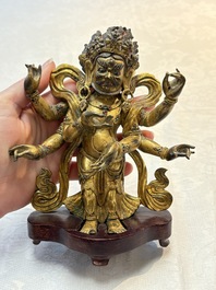A Sino-Tibetan gilt-bronze figure of White Mahakala on wooden stand, 18th C.