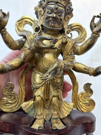 A Sino-Tibetan gilt-bronze figure of White Mahakala on wooden stand, 18th C.