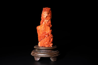A fine Chinese red coral sculpture of Guanyin seated on a lotus throne on a wooden stand, 19/20th C.