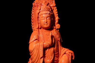 A fine Chinese red coral sculpture of Guanyin seated on a lotus throne on a wooden stand, 19/20th C.