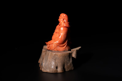 A Chinese red coral sculpture of a Milefo Buddha on wooden stand, 19/20th C.
