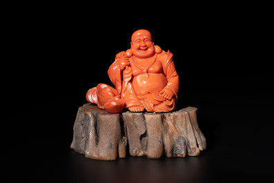 A Chinese red coral sculpture of a Milefo Buddha on wooden stand, 19/20th C.