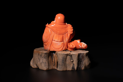 A Chinese red coral sculpture of a Milefo Buddha on wooden stand, 19/20th C.