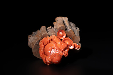 A Chinese red coral sculpture of a Milefo Buddha on wooden stand, 19/20th C.