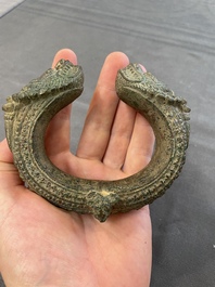 A bronze mirror, a bracelet with a royal or noble emblem and a bronze bracelet with two tiger heads, Cambodia, 12th C.
