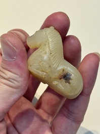 A Chinese white and russet jade pendant in the form of a horse, Song/Ming