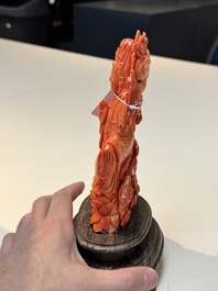 A fine Chinese red coral sculpture of Guanyin seated on a lotus throne on a wooden stand, 19/20th C.