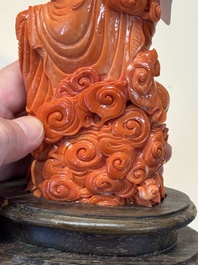 A fine Chinese red coral sculpture of Guanyin seated on a lotus throne on a wooden stand, 19/20th C.