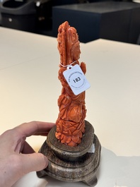 A fine Chinese red coral sculpture of Guanyin seated on a lotus throne on a wooden stand, 19/20th C.