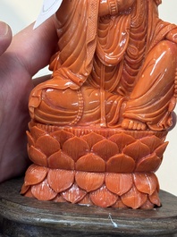 A fine Chinese red coral sculpture of Guanyin seated on a lotus throne on a wooden stand, 19/20th C.