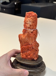 A fine Chinese red coral sculpture of Guanyin seated on a lotus throne on a wooden stand, 19/20th C.