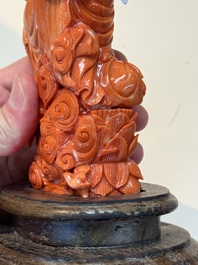 A fine Chinese red coral sculpture of Guanyin seated on a lotus throne on a wooden stand, 19/20th C.