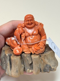 A Chinese red coral sculpture of a Milefo Buddha on wooden stand, 19/20th C.