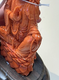 A fine Chinese red coral sculpture of Guanyin seated on a lotus throne on a wooden stand, 19/20th C.