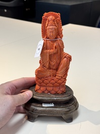 A fine Chinese red coral sculpture of Guanyin seated on a lotus throne on a wooden stand, 19/20th C.