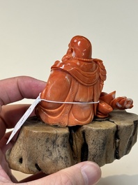 A Chinese red coral sculpture of a Milefo Buddha on wooden stand, 19/20th C.