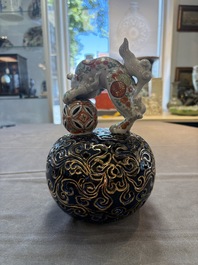 A Japanese Kutani group of a Shishi standing on an openworked brocade ball, 20th C.
