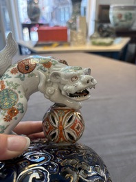 A Japanese Kutani group of a Shishi standing on an openworked brocade ball, 20th C.