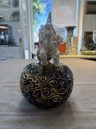 A Japanese Kutani group of a Shishi standing on an openworked brocade ball, 20th C.