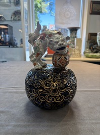 A Japanese Kutani group of a Shishi standing on an openworked brocade ball, 20th C.