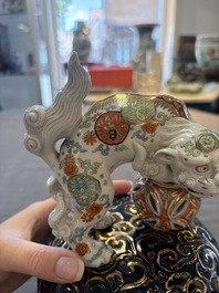 A Japanese Kutani group of a Shishi standing on an openworked brocade ball, 20th C.