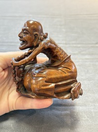 A Chinese fine huanghuali sculpture of a Luohan on a zitan stand, Qianlong mark, 19/20th C.