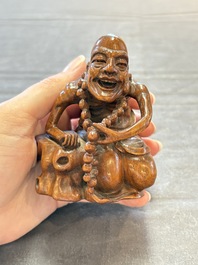 A Chinese fine huanghuali sculpture of a Luohan on a zitan stand, Qianlong mark, 19/20th C.