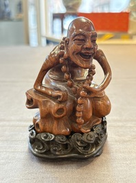 A Chinese fine huanghuali sculpture of a Luohan on a zitan stand, Qianlong mark, 19/20th C.