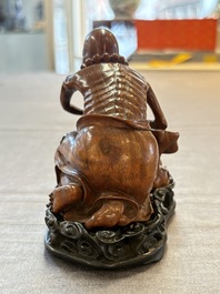 A Chinese fine huanghuali sculpture of a Luohan on a zitan stand, Qianlong mark, 19/20th C.