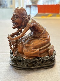 A Chinese fine huanghuali sculpture of a Luohan on a zitan stand, Qianlong mark, 19/20th C.
