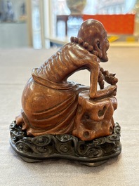 A Chinese fine huanghuali sculpture of a Luohan on a zitan stand, Qianlong mark, 19/20th C.