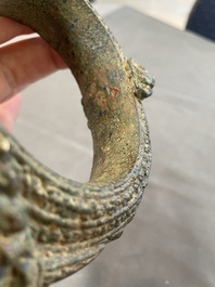 A bronze mirror, a bracelet with a royal or noble emblem and a bronze bracelet with two tiger heads, Cambodia, 12th C.