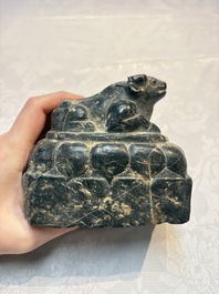 A Chinese carved black stone paper weight in the shape of a reclining buffalo on a lotus throne, Northern and Southern dynasties
