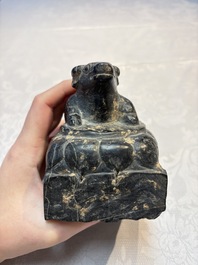 A Chinese carved black stone paper weight in the shape of a reclining buffalo on a lotus throne, Northern and Southern dynasties